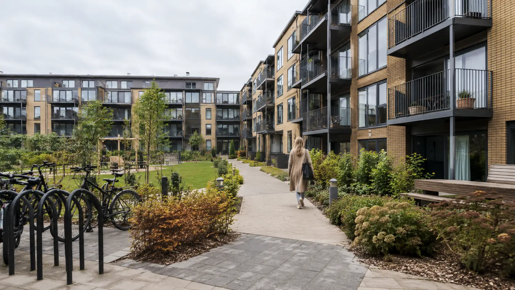 Lejlighedskompleks med udearealer og der går en kvinde